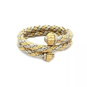 May include: A gold and silver braided bangle bracelet with two round, textured gold accents.