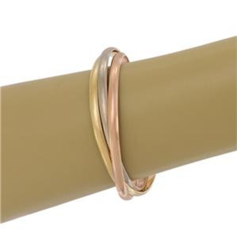 May include: A triple band ring with three bands of gold, rose gold, and white gold intertwined. The bands are polished and have a smooth, shiny finish.