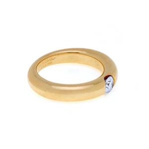May include: A gold band ring with a single round diamond set in the center. The ring is smooth and has a polished finish.