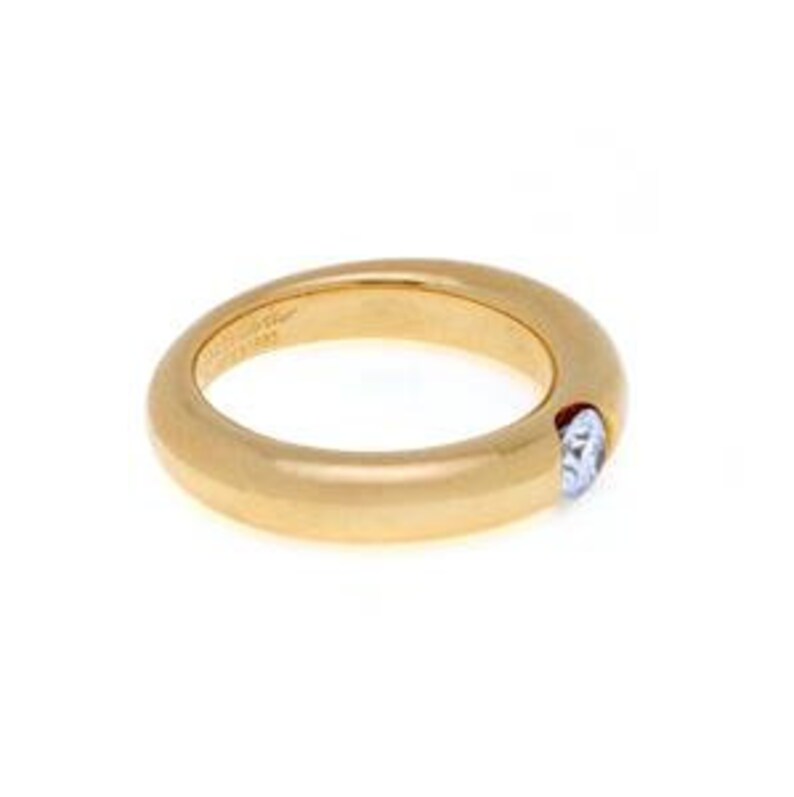 May include: A gold band ring with a single round diamond set in the center. The ring is smooth and has a polished finish.