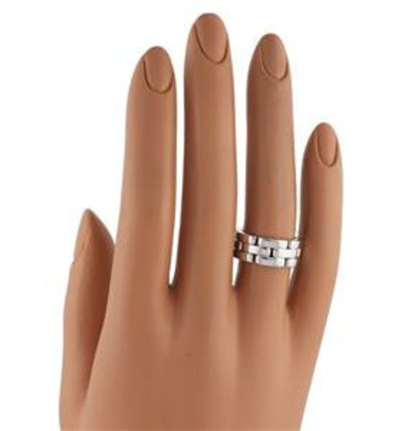 May include: A silver wedding band with a textured, linked design. The band is made of metal and has a polished finish.