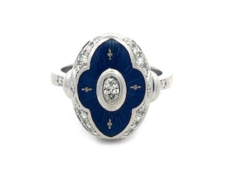 Puede incluir: Un anillo de oro blanco con un centro de esmalte azul y un diamante. El anillo está engastado con pequeños diamantes alrededor del borde del esmalte.