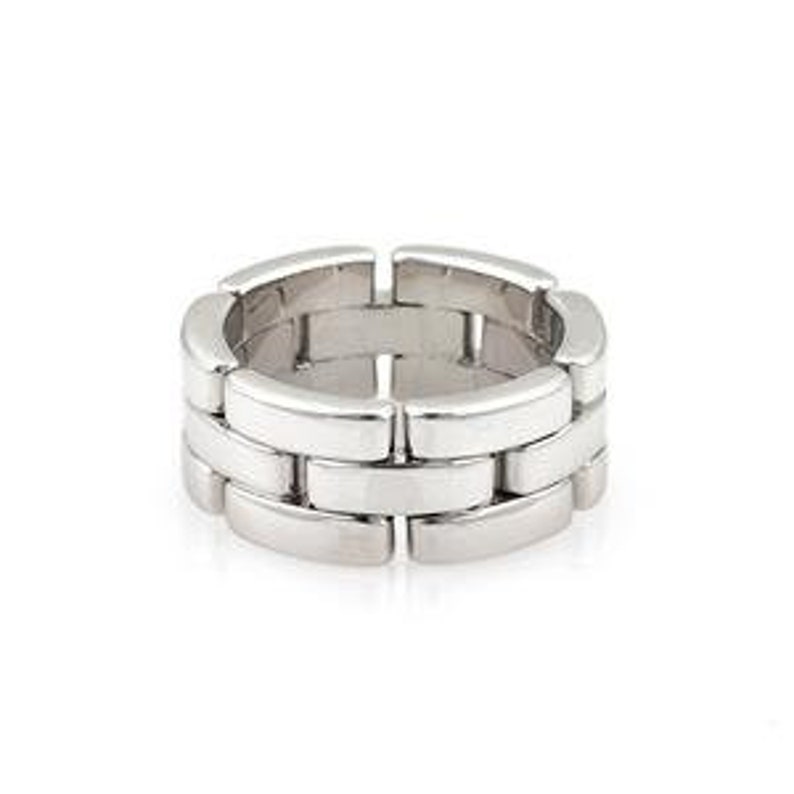 May include: A silver, polished, metal ring with a linked, rectangular design. The ring is a classic style and is made of multiple connected pieces.