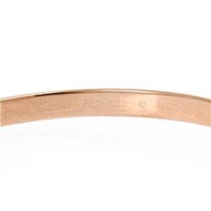 May include: Close-up of the inside of a gold Cartier Love bracelet. The inscription reads 'Cartier 750 18K  ©  Made in France'.