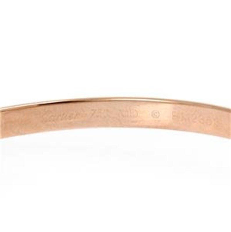 May include: Close-up of the inside of a gold Cartier Love bracelet. The inscription reads 'Cartier 750 18K  ©  Made in France'.