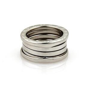 May include: A silver-toned ring with a stacked design. The ring features multiple bands, with a slightly raised outer band displaying engraved text. The bands are smooth and have a polished finish, reflecting light.