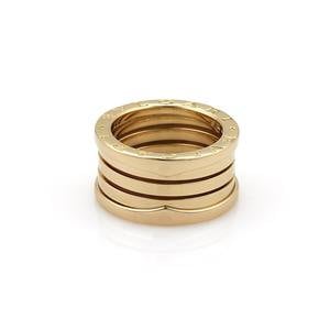 May include: A gold ring with four bands, each with a textured surface and a row of small dots. The ring is a popular style of jewelry.