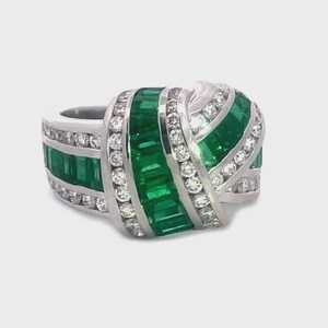 May include: A silver ring featuring a design of emerald-cut green gemstones and round white gemstones. The ring has a unique, layered design with the green stones set in a horizontal pattern and the white stones set in a curved pattern.