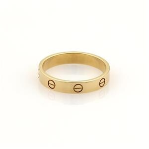 May include: A yellow gold Cartier Love wedding band. The band features a polished finish and is adorned with screw motifs along its surface. This iconic design is a classic symbol of love and commitment. The ring is shown against a plain white background.