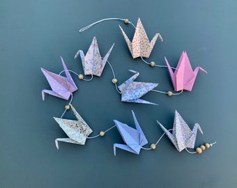 Guirnalda de grullas de origami en tonos rosas, azules y morados.