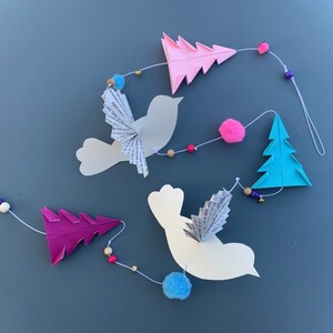 Garland of birds, fir trees, pompoms and small bells, shades of pink, green and blue