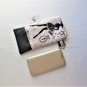 May include: A black and white patterned phone case with a black leather accent, a star-shaped charm, and a gold-colored smartphone. The case features a ballerina design and the number 6.