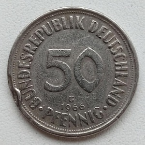 May include: A silver 1966 German 50 Pfennig coin. The coin features the text "BUNDESREPUBLIK DEUTSCHLAND" and "PFENNIG". The number "50" is prominently displayed, along with the year "1966".