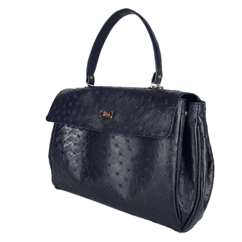 May include: A navy blue handbag with a textured surface and a top handle. The bag features a flap closure with a gold-colored clasp. The handbag has a structured design and a classic, elegant style.