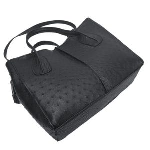 May include: A black ostrich leather tote bag with a top zipper closure and two handles.