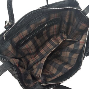 May include: Black leather tote bag with a plaid lining. The bag has a zipper closure and two top handles.
