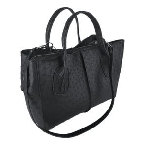 May include: Black leather handbag with a textured ostrich-like pattern. The bag has two top handles and a long shoulder strap.
