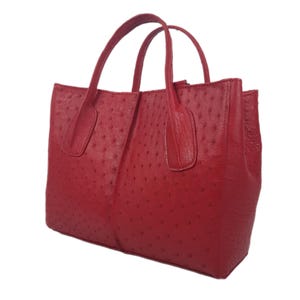 May include: A red ostrich leather tote bag with a structured shape and two top handles.