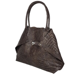 May include: A brown leather handbag with a crocodile-embossed pattern and a silver clasp.