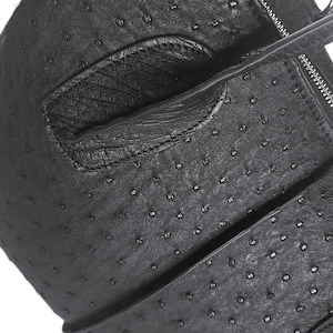 May include: Black leather bag with a textured ostrich-like pattern. The bag has a flap closure and a zipper detail.