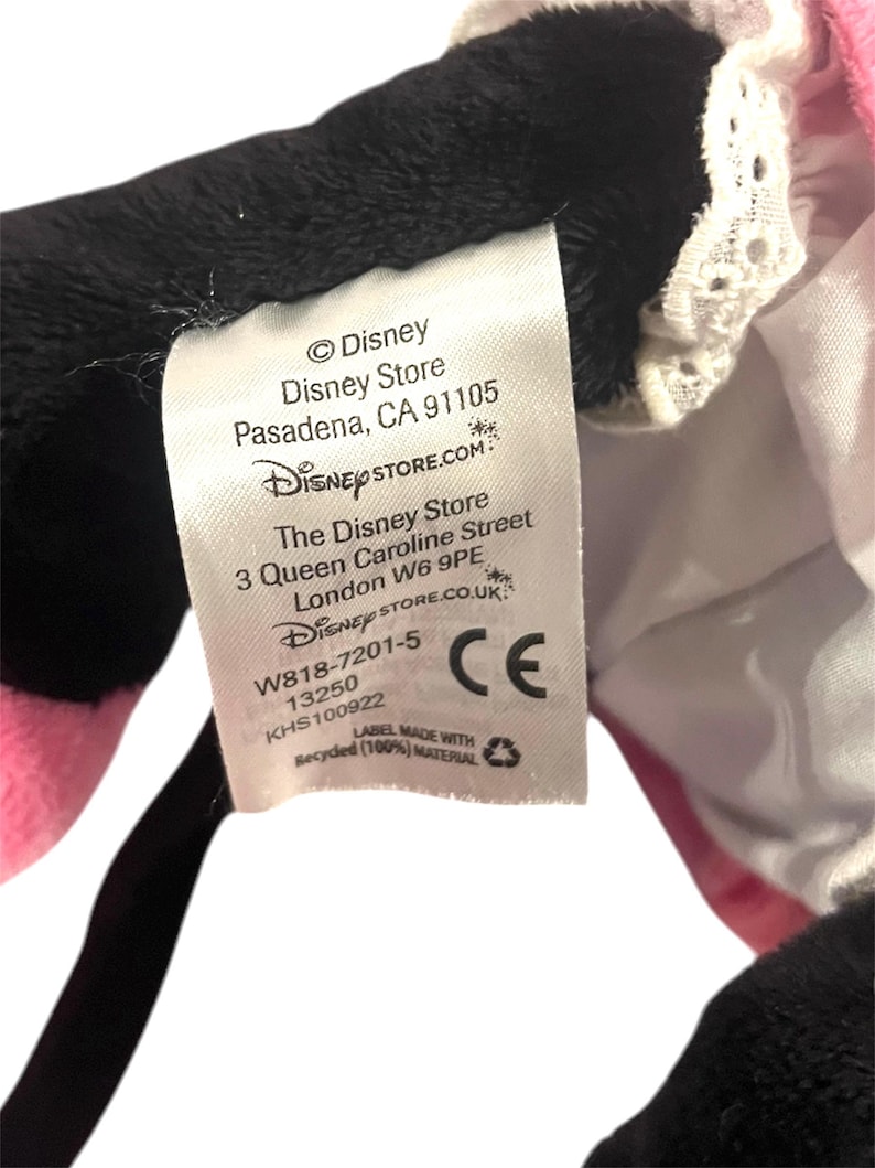May include: White tag with black text on a black and pink plush toy. The tag reads: &copy;Disney Disney Store Pasadena, CA 91105 DISNEYSTORE.COM The Disney Store 3 Queen Caroline Street London W6 9PE DISNEYSTORE.CO.UK W818-7201-5 13250 KHS100922 CE LABEL MADE WITH Recycled (100%) MATERIAL