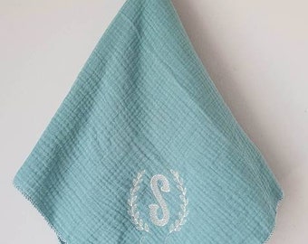 Embroidered and personalized baby swaddle with an initial wreath of leaves and a first name. Several colors to choose from.