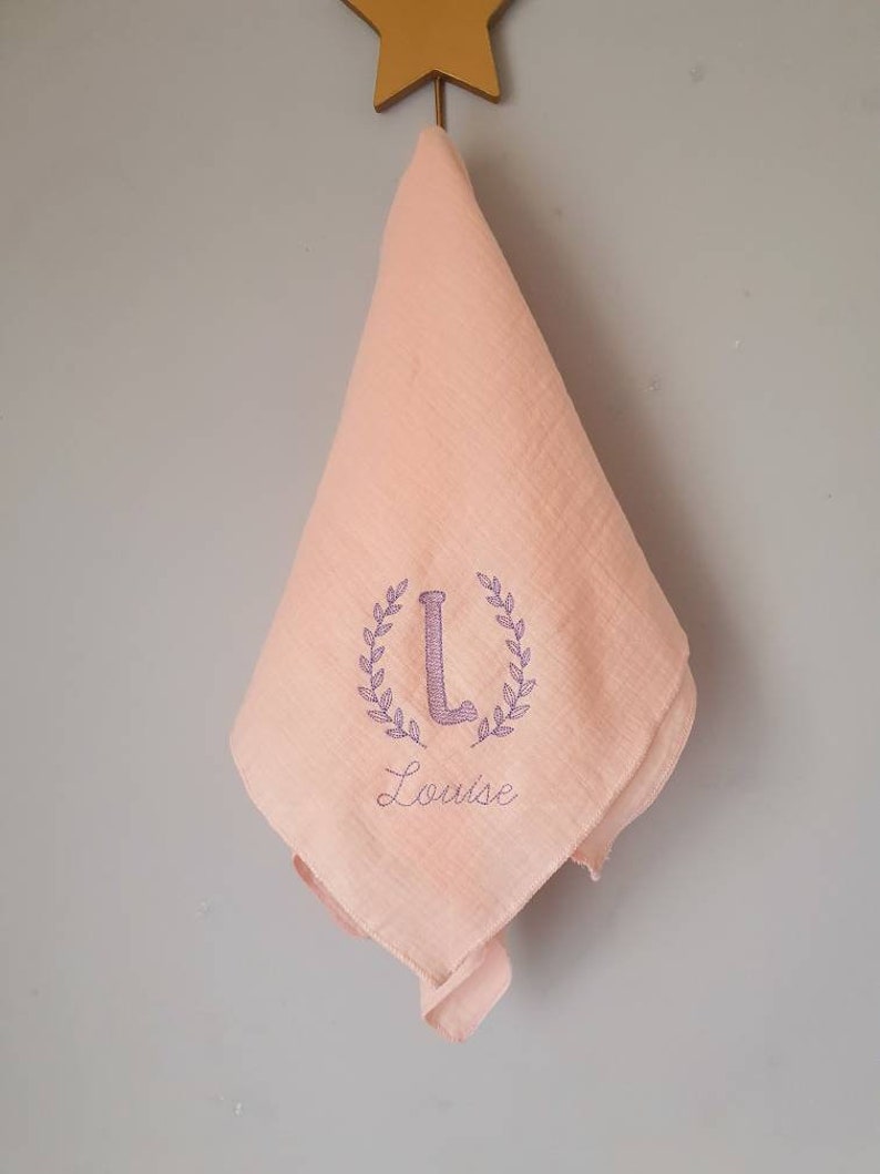 Embroidered and personalized baby swaddle with an initial wreath of leaves and a first name. Several colors to choose from. Rose Blush