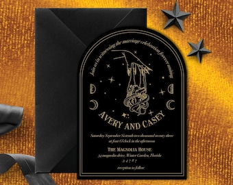 May include: Black and gold wedding invitation with a hand holding a snake and a crescent moon. The text reads "Join us in witnessing the marriage celebration forever uniting Avery and Casey. Saturday, September Sixteenth, two thousand twenty-three at four o'clock in the afternoon. The Magnolia House, 54 magnolia drive, Winter Garden, Florida 34787. Reception to follow."