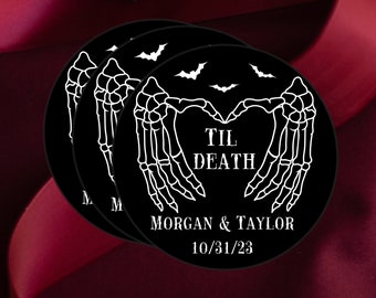 May include: Black round stickers with a skeleton hand heart design, bats, and the text "TIL DEATH" with names and a date. The stickers are stacked on a dark red background.