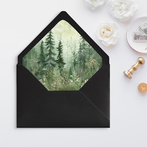 May include: Black envelope with a square window showing a watercolor painting of a misty forest with green trees and white flowers.
