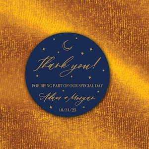 K&ouml;nnte beinhalten: Ein marineblauer Kreis mit goldenen Sternen und einem Halbmond. Der Text "Danke!" ist in goldener Kursivschrift geschrieben. Unter dem Text steht "F&uuml;r die Teilnahme an unserem besonderen Tag" und "Adam & Morgan" in goldener Kursivschrift. Das Datum "10/31/23" ist in Gold unter den Namen geschrieben.