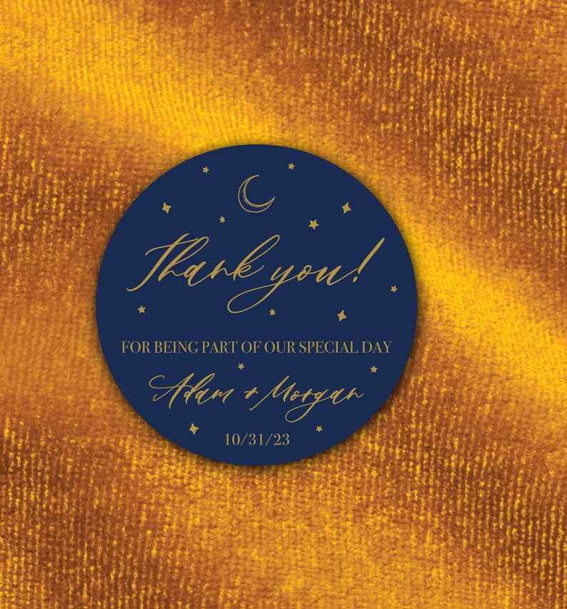 K&ouml;nnte beinhalten: Ein marineblauer Kreis mit goldenen Sternen und einem Halbmond. Der Text "Danke!" ist in goldener Kursivschrift geschrieben. Unter dem Text steht "F&uuml;r die Teilnahme an unserem besonderen Tag" und "Adam & Morgan" in goldener Kursivschrift. Das Datum "10/31/23" ist in Gold unter den Namen geschrieben.