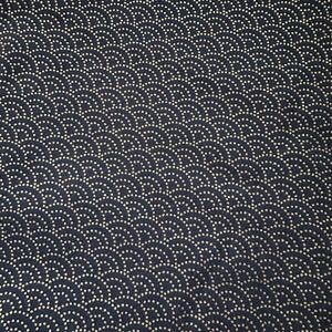 Op de afbeelding: Een donkerblauwe stof met een herhalend patroon van kleine gouden cirkels die in een golfvormige opstelling zijn gerangschikt.