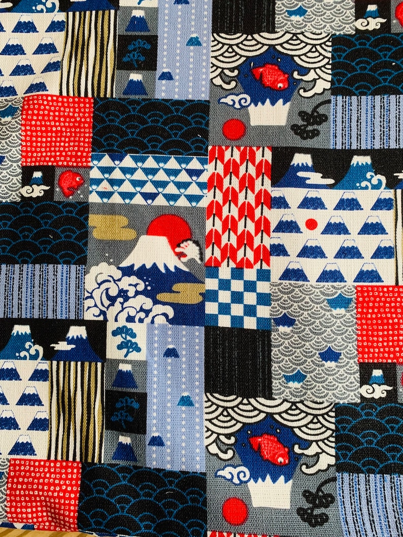 Op de afbeelding: Een patchwork stof met een Japans ge&iuml;nspireerd ontwerp. De stof heeft een verscheidenheid aan patronen, waaronder bergen, golven, vissen en geometrische vormen. De stof is in tinten blauw, rood, wit en zwart.