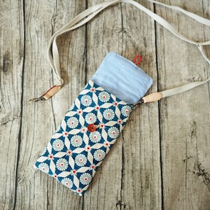 May include: A blue and white patterned fabric pouch with a light blue fabric lining. The pouch is attached to a white strap.
