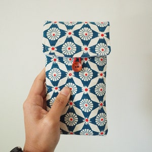 May include: A blue and white fabric pouch with a red and white floral pattern. The pouch has a red button closure.