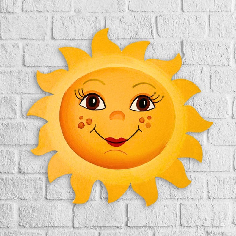 Puede incluir: Un sol amarillo con una cara sonriente, ojos marrones y labios rosados. El sol tiene un fondo de pared de ladrillo blanco.