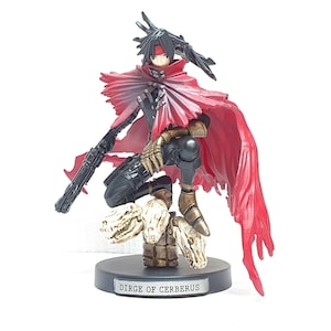 May include: A detailed figurine of a character in a dynamic pose, wearing a red cape and holding a gun. The figure is kneeling on a base with three skull-shaped objects. The base reads "DIRGE OF CERBERUS".