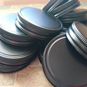 May include: A stack of black metal jar lids with a ridged edge.