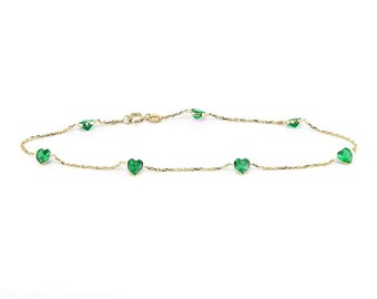 May include: A delicate gold chain bracelet with five green heart-shaped gemstones.