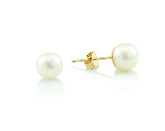 Puede incluir: Un par de pendientes de oro con perlas. Cada pendiente tiene una perla blanca.