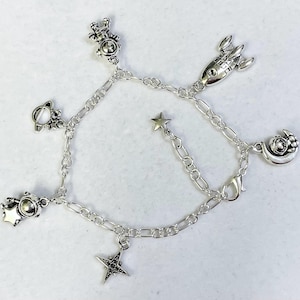 May include: A silver charm bracelet featuring astronaut, rocket, star and moon charms. The bracelet is made from a delicate silver chain.