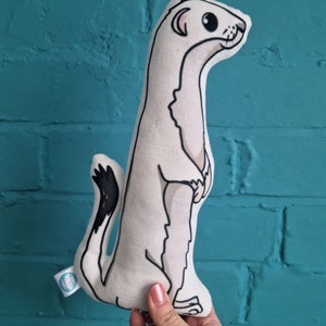 May include: A white plush toy shaped like a weasel standing on its hind legs. The toy has black eyes, a black nose, and a black tail.