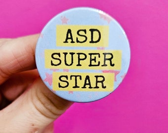 May include: A blue and white button with pink stars and the text "ASD SUPER STAR" in yellow.