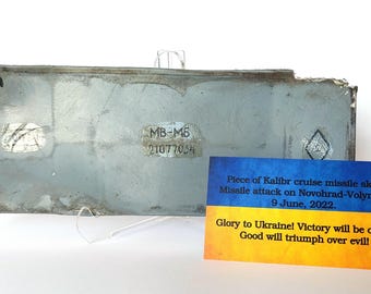 May include: A piece of a gray cruise missile skin with the text "MB-M6 21077054". A card with the Ukrainian flag has text about a missile attack on June 9, 2022, and the phrase "Glory to Ukraine! Victory will be ours!"