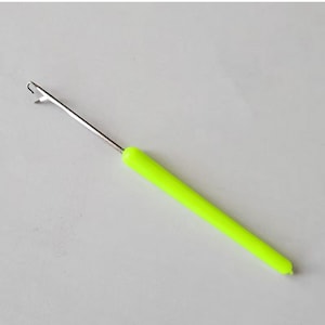 Puede incluir: Un gancho de ganchillo de plástico verde con un gancho de metal en el extremo.