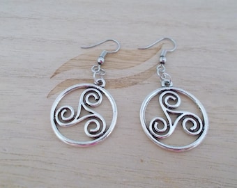 May include: A pair of silver earrings with a circular design featuring a Celtic knot, also known as a triskelion. The earrings have a simple hook closure.