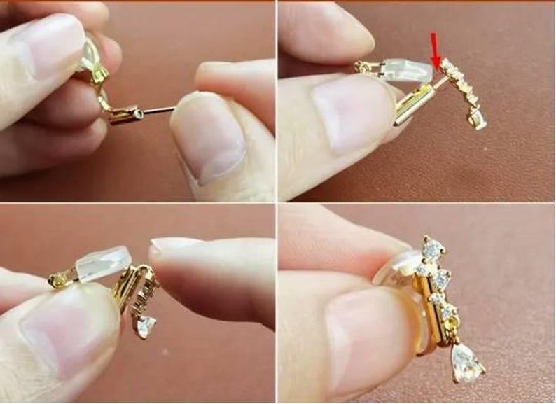 May include: A gold-toned clip-on earring featuring a curved bar set with small clear stones and a single pear-shaped drop stone. The earring includes a clear silicone cushion pad on the clip mechanism for comfort and a red arrow indicating placement.