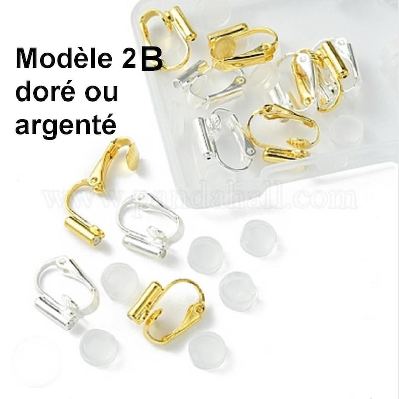 May include: A collection of gold and silver-toned metal clip-on earring findings with hinged mechanisms and small, clear, circular silicone pads. The text Mod&egrave;le 2B dor&eacute; ou argent&eacute; is visible in the upper left corner of the image.