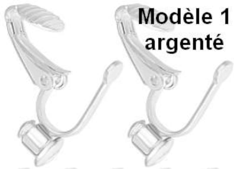 May include: A pair of silver-toned metal clip-on earring findings featuring a hinged mechanism with a textured grip pad at the top and a flat circular base at the bottom for attaching decorative elements. The text Mod&egrave;le 1 argent&eacute; is visible.